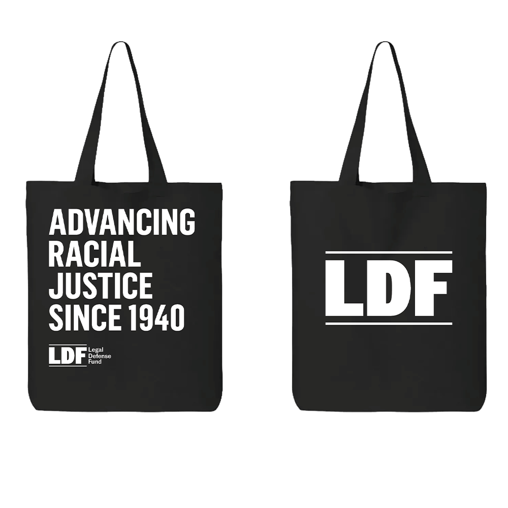 Two black canvas tote bags shown side by side on a white background. The left bag has white text reading 'ADVANCING RACIAL JUSTICE SINCE 1940' with a small LDF logo below.
