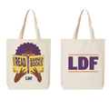 Two cream canvas tote bags shown side by side on a white background. The left bag features a graphic of a person with an afro holding a book that reads 'I READ BANNED BOOKS' with 'LDF' below, and the right bag displays 'LDF' in large purple letters with thin orange lines.