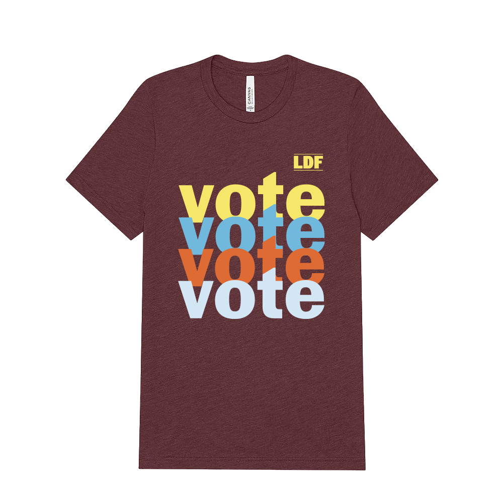 A heathered maroon short-sleeve t-shirt with a stacked 'vote' graphic in yellow, light blue, orange, and white on the front, plus a small yellow 'LDF' logo in the upper right of the print. The shirt is shown flat against a solid white background.