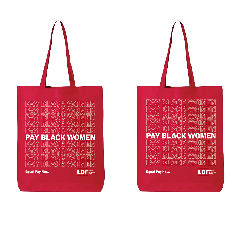 Two red reusable tote bags shown side by side on a plain white background. Each bag has long handles, a repeating light pink 'PAY BLACK WOMEN' text pattern, and bold white text reading 'PAY BLACK WOMEN' with smaller white text 'Equal Pay Now.